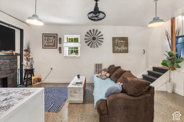 Polished concrete flooring, recessed lighting, and a dark wood-clad fireplace