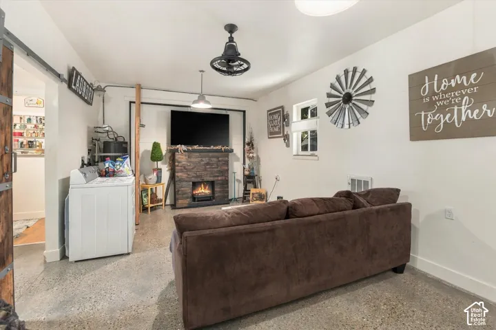Concrete flooring, wood-finish fireplace surround with an electric insert, and a wood barn door on a metal track