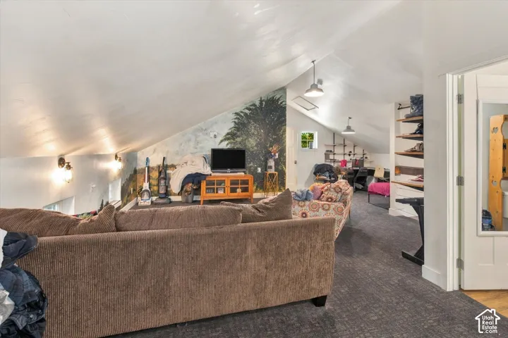 Sloped ceilings with exposed beams, recessed lighting, wall-mounted sconces, and a window with natural light