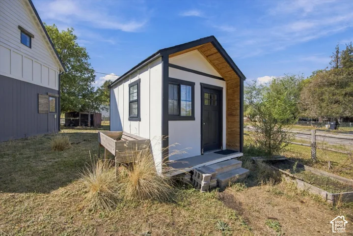 White vertical siding with black trim, black entry door, and a small porch with concrete steps