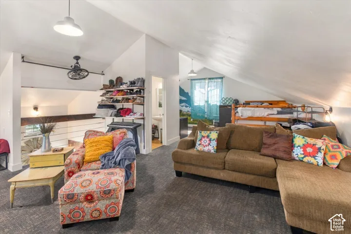 Vaulted ceilings, exposed wood railing, built-in shelving, and a prominent ceiling fan