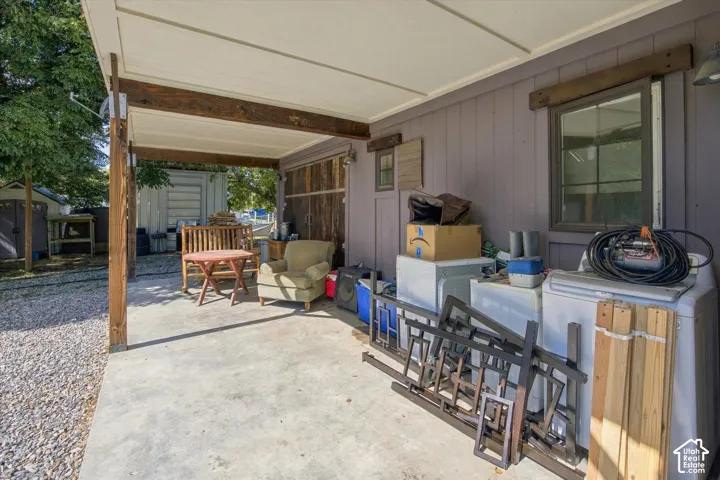 Covered concrete patio featuring exposed wooden beams and a gravel-covered area