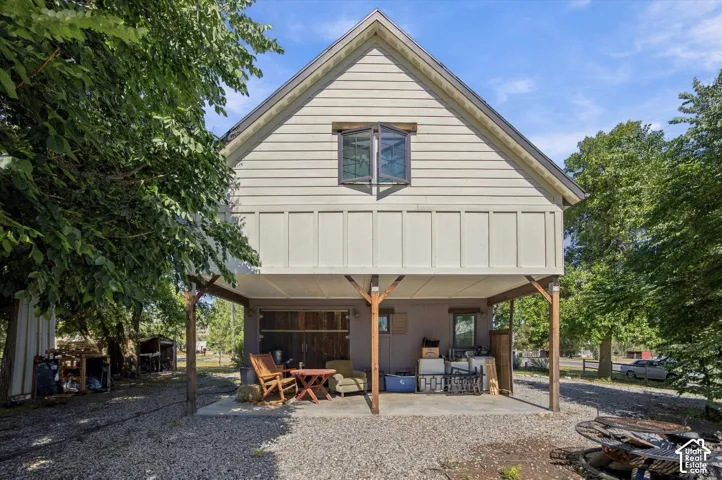 Gable roofline with siding and board and batten facade, supported by exposed wood posts, over a concrete patio