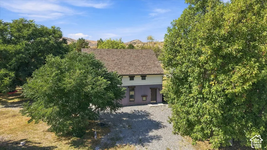 Two-story residence with a shingle roof and a gravel driveway