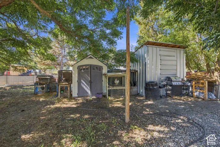 Shaded outdoor area featuring two storage sheds, one with double gray doors and the other a metal structure with a sloped roof