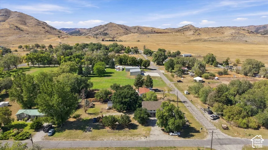 Expansive rural landscape featuring a mountainous backdrop, scattered residential properties, and mature trees