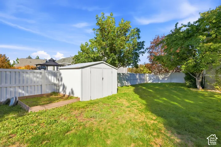 Expansive green lawn, white privacy fencing, mature trees, and a utility shed