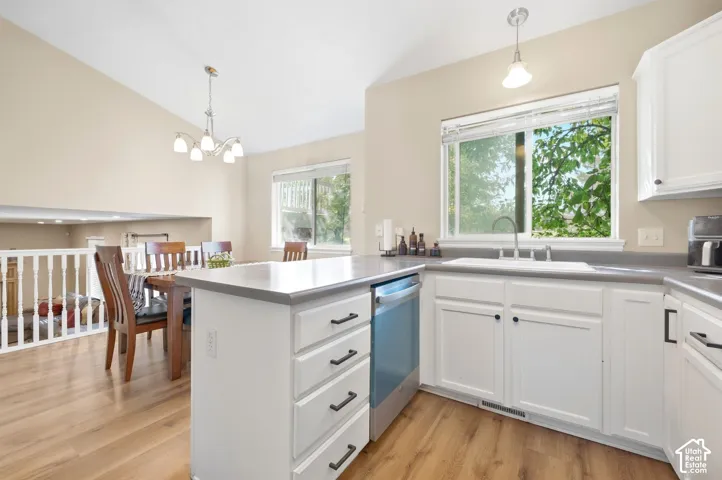 Kitchen featuring white cabinetry, wood-finish flooring, a stainless steel dishwasher, and an integrated sink