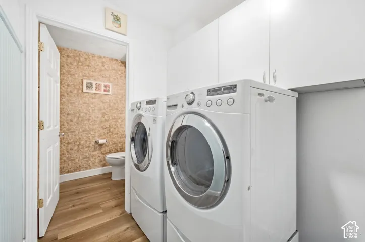 Laundry area with wood-finish flooring and white upper cabinetry