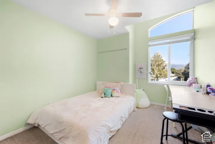 Arched transom window above a large picture window, ceiling fan with integrated lighting, and neutral carpeting