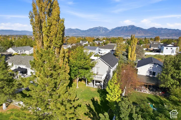Expansive backyard with a manicured lawn, established trees, and a two-story residence featuring a balcony