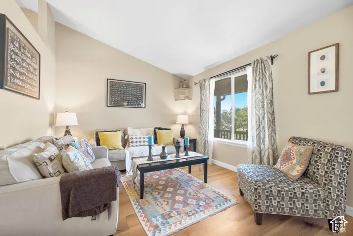 Vaulted ceilings, wood-finish flooring, and a large window with natural light