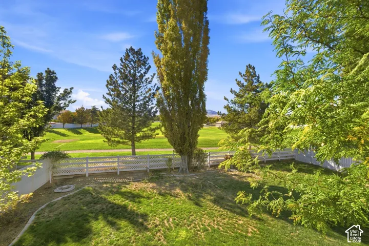 Expansive green lawn with a white lattice fence and mature trees