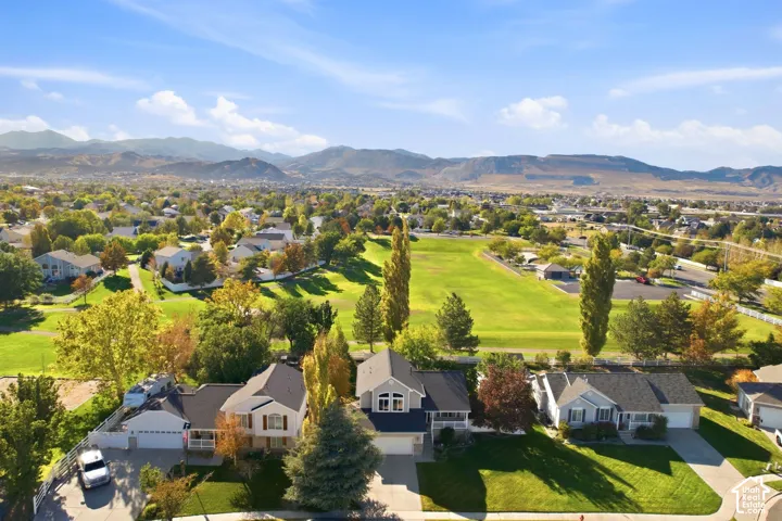 Expansive green spaces and mature trees surround the property, with mountainous terrain visible in the distance