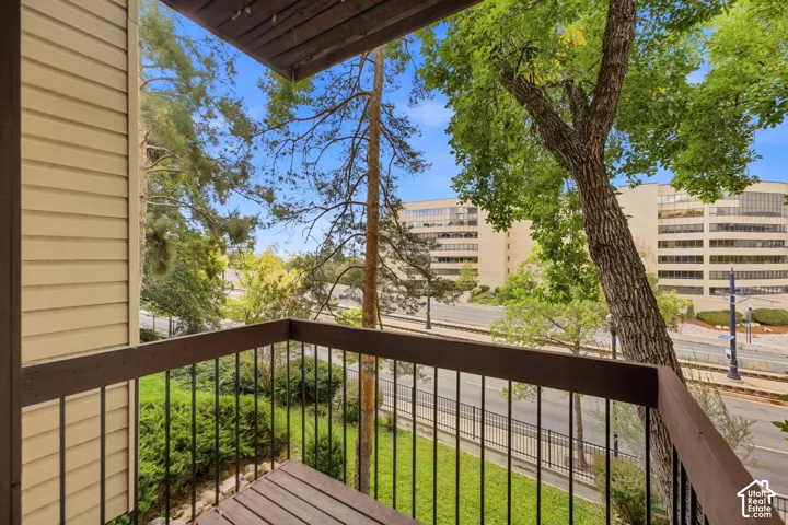 Balcony with slatted wood flooring, dark wood railing, and black metal spindles