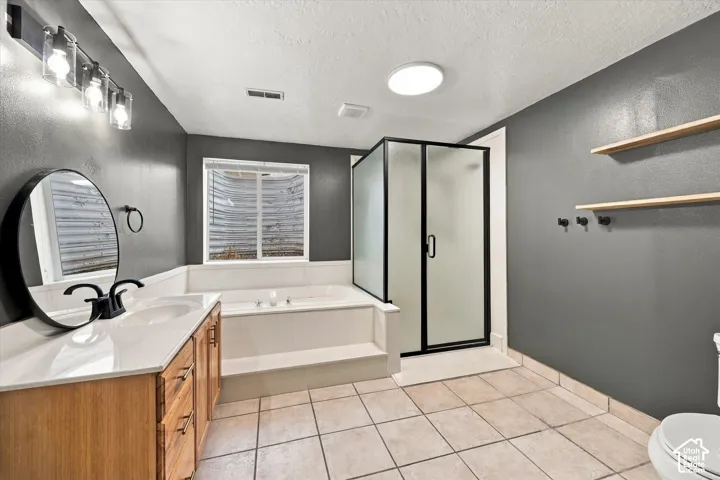ADU Basement - Tile flooring, built-in soaking tub, glass-enclosed shower, wood-finish vanity with countertop, and recessed lighting