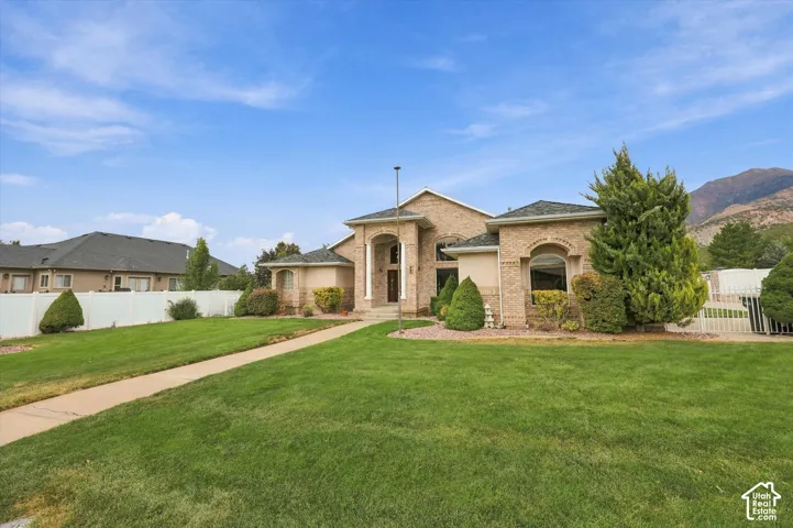 Brick exterior with arched windows, prominent entry columns, extensive lawn, and a white picket fence
