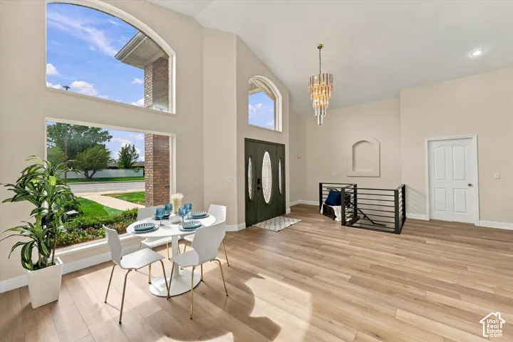 Vaulted ceiling, wood-finish flooring, arched windows, modern chandelier, and iron railing