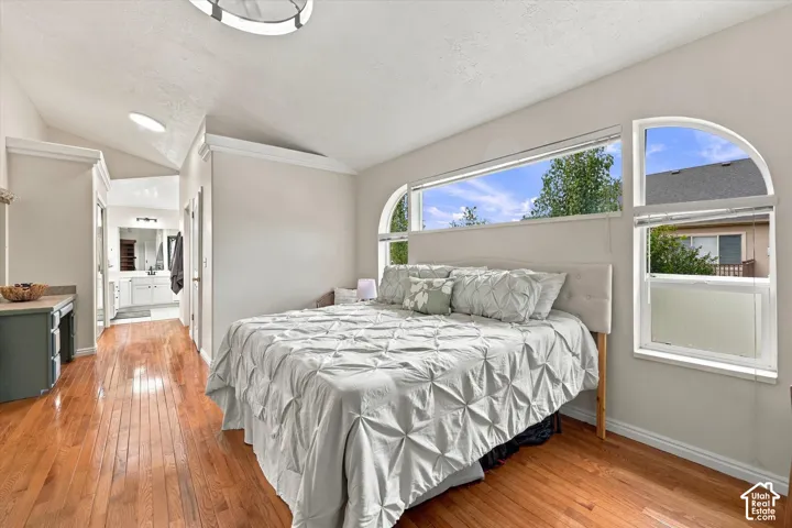 Primary Bedroom - Hardwood flooring throughout, vaulted ceiling, and arched windows