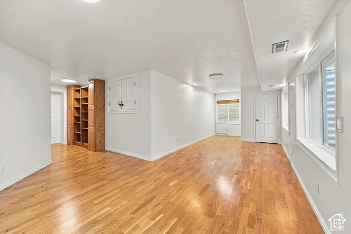 ADU Basement - Wood-finish flooring, recessed lighting, built-in shelving, multiple windows, and a paneled door