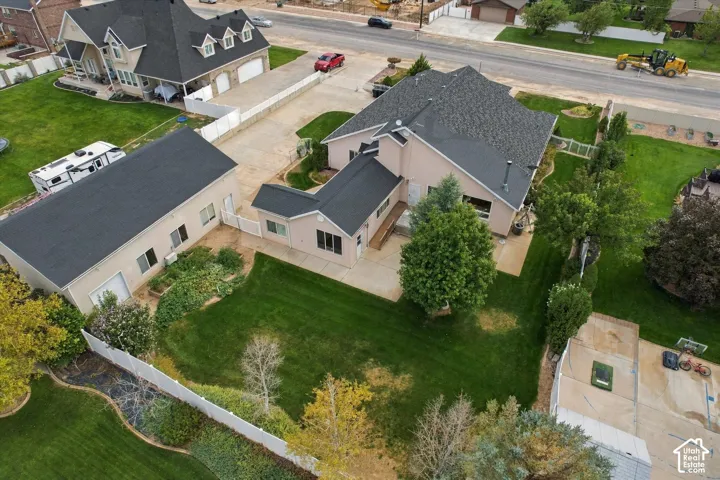 Expansive rear yard featuring a manicured lawn, mature trees, and a concrete patio