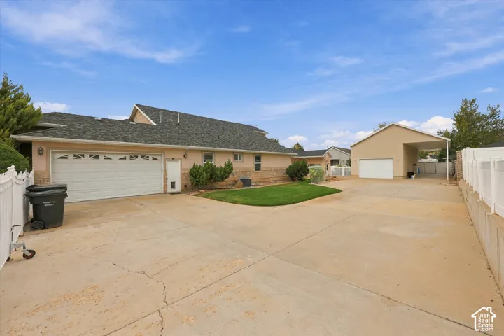 Expansive concrete driveway, attached two-car garage, detached garage with carport, and manicured lawn area