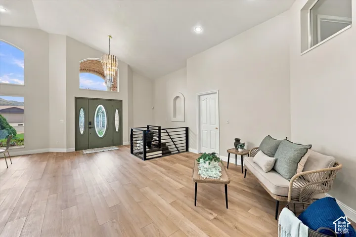 Vaulted ceilings with recessed lighting, wood-finish flooring, and a contemporary chandelier