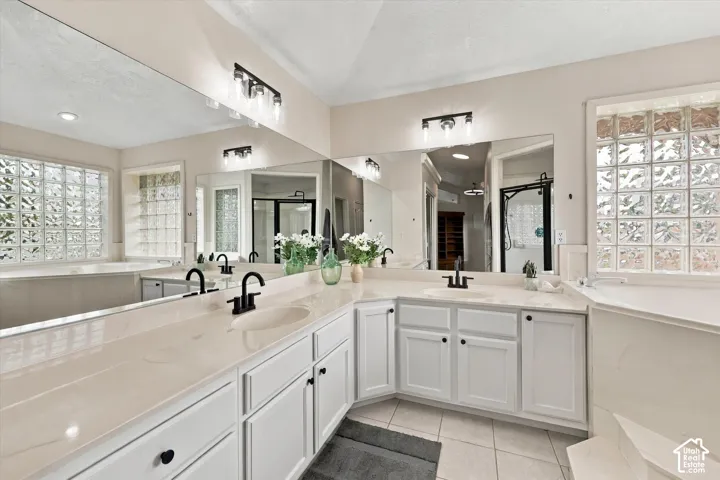 Primary Bathroom - Dual vanity with integrated sinks, white cabinetry, extensive counter space, and a large wall-mounted mirror