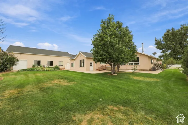 Expansive green lawn with mature trees and a paved patio area