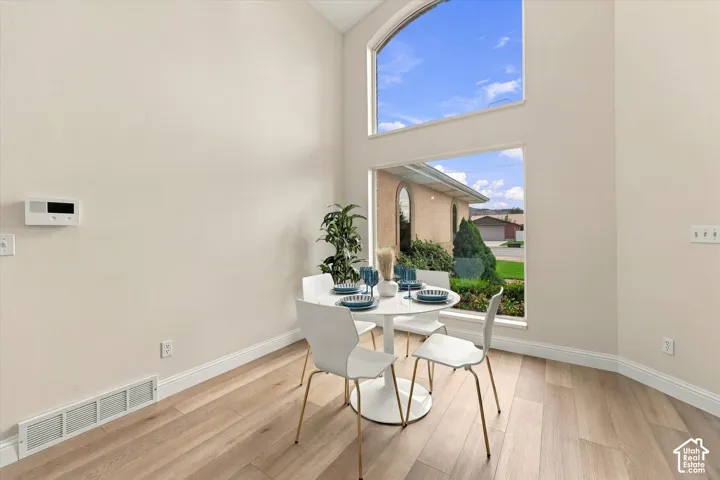 Vaulted ceiling with an arched window, large rectangular windows, light wood-finish flooring, and light-toned walls