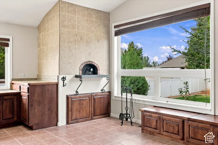 Built-in pizza oven with tile surround, wood-finish cabinetry, tile flooring, and large windows
