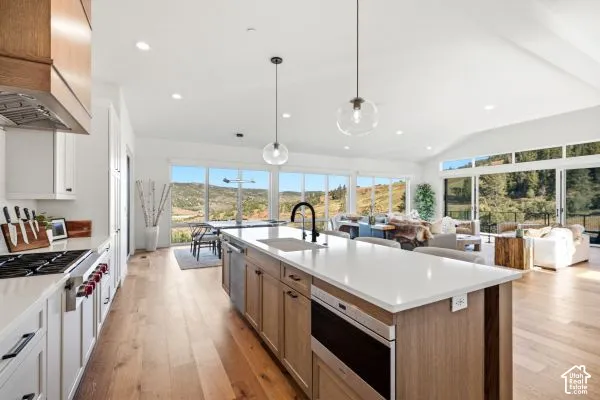 Open concept kitchen with a central island, recessed lighting, wood-finish flooring, and expansive windows