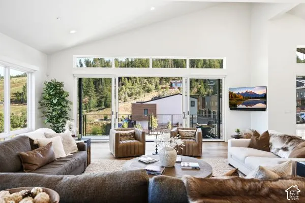 Vaulted ceiling with recessed lighting, large sliding glass doors, white walls, and wood-finish flooring