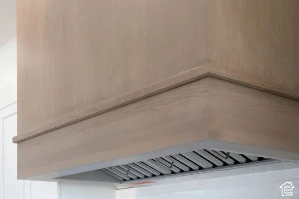 Custom wood-finish range hood with integrated stainless steel ventilation system and decorative molding
