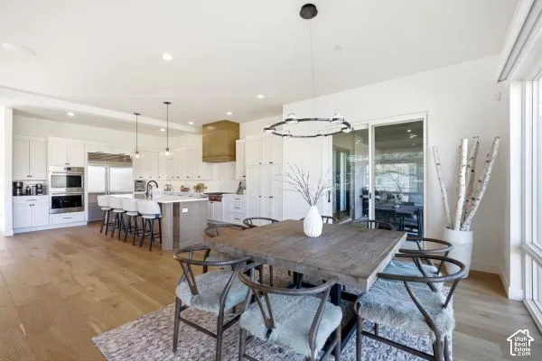 Open-concept kitchen and dining area featuring light wood-finish flooring, a kitchen island with seating, white cabinetry, stainless steel appliances, and a sliding glass door