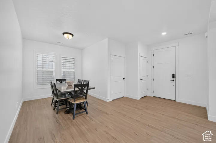 Wood-finish flooring, white walls, two windows with horizontal blinds, flush mount light fixture, and white interior doors with black hardware