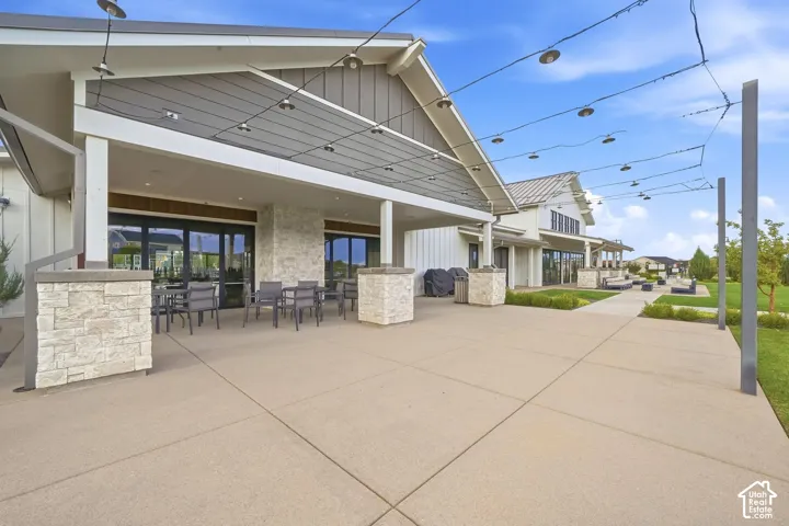 Expansive concrete patio with decorative string lighting and stone-clad columns