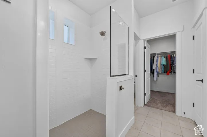 Walk-in shower with tiled walls and floor, two transom windows, and an integrated corner shelf