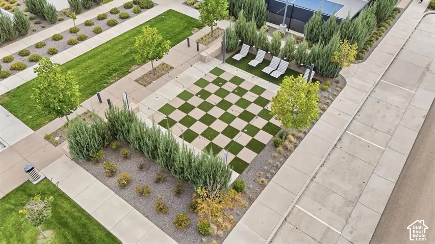 Checkered outdoor common area with integrated landscaping, perimeter shrubbery, and paved pathways