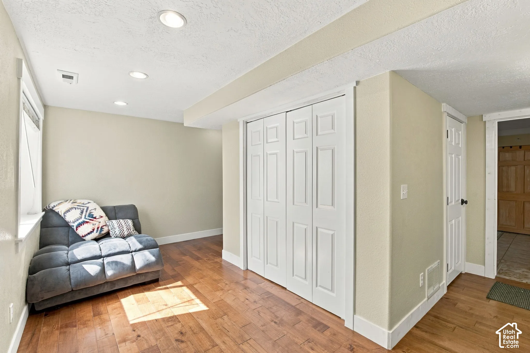 Recessed ceiling lighting, wood-finish flooring, white bi-fold closet doors, and white paneled interior doors