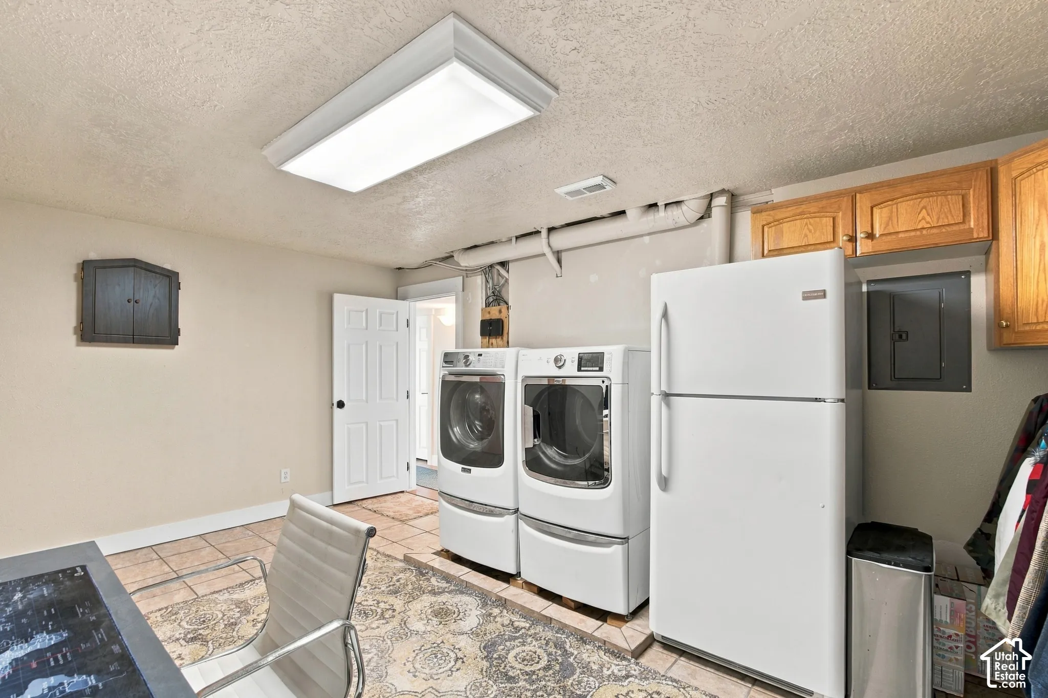 Tile flooring with a flush-mounted ceiling light fixture, featuring a laundry area with built-in cabinetry