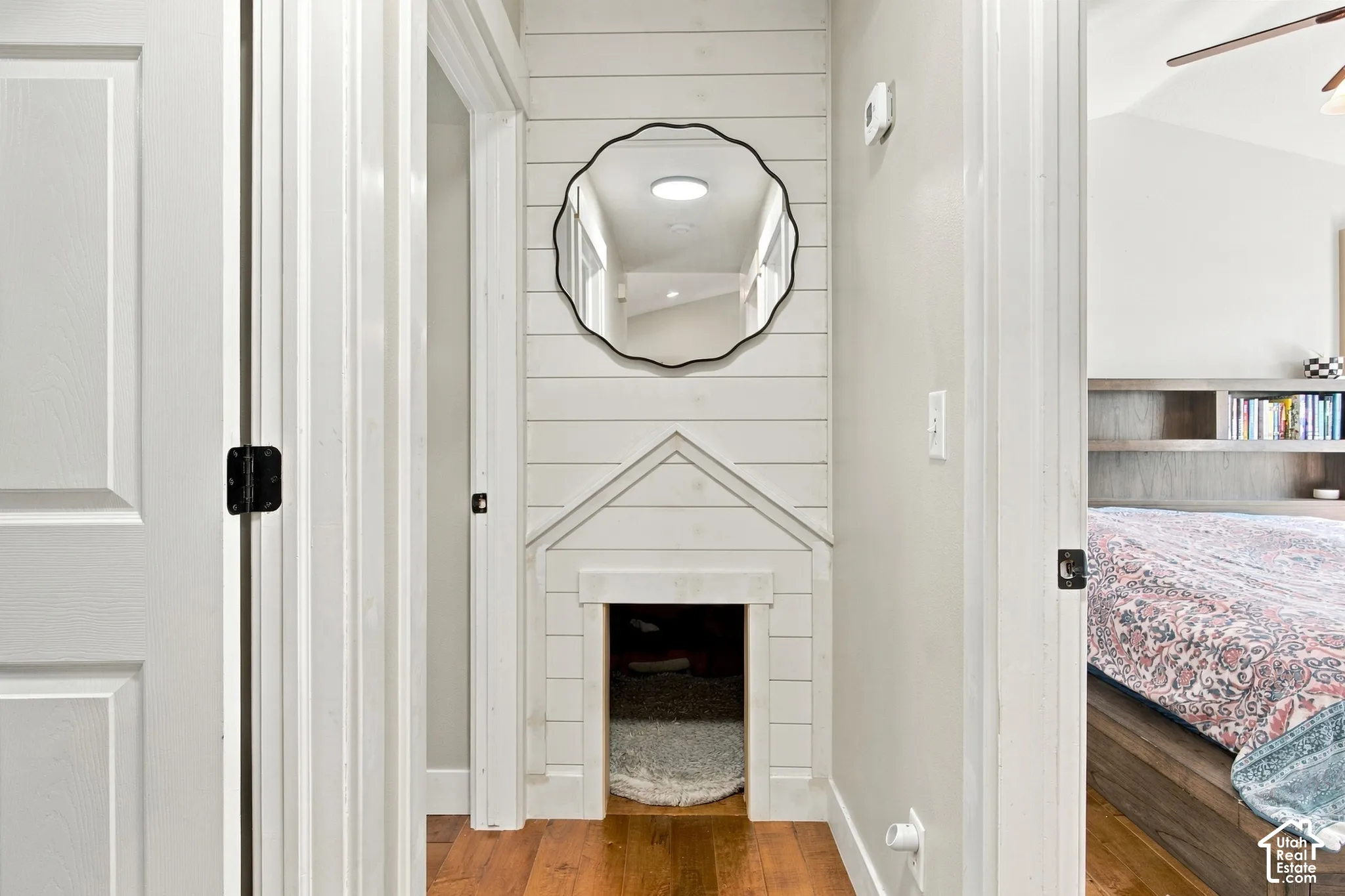 Hallway with hardwood flooring, white paneled walls, built-in pet nook.