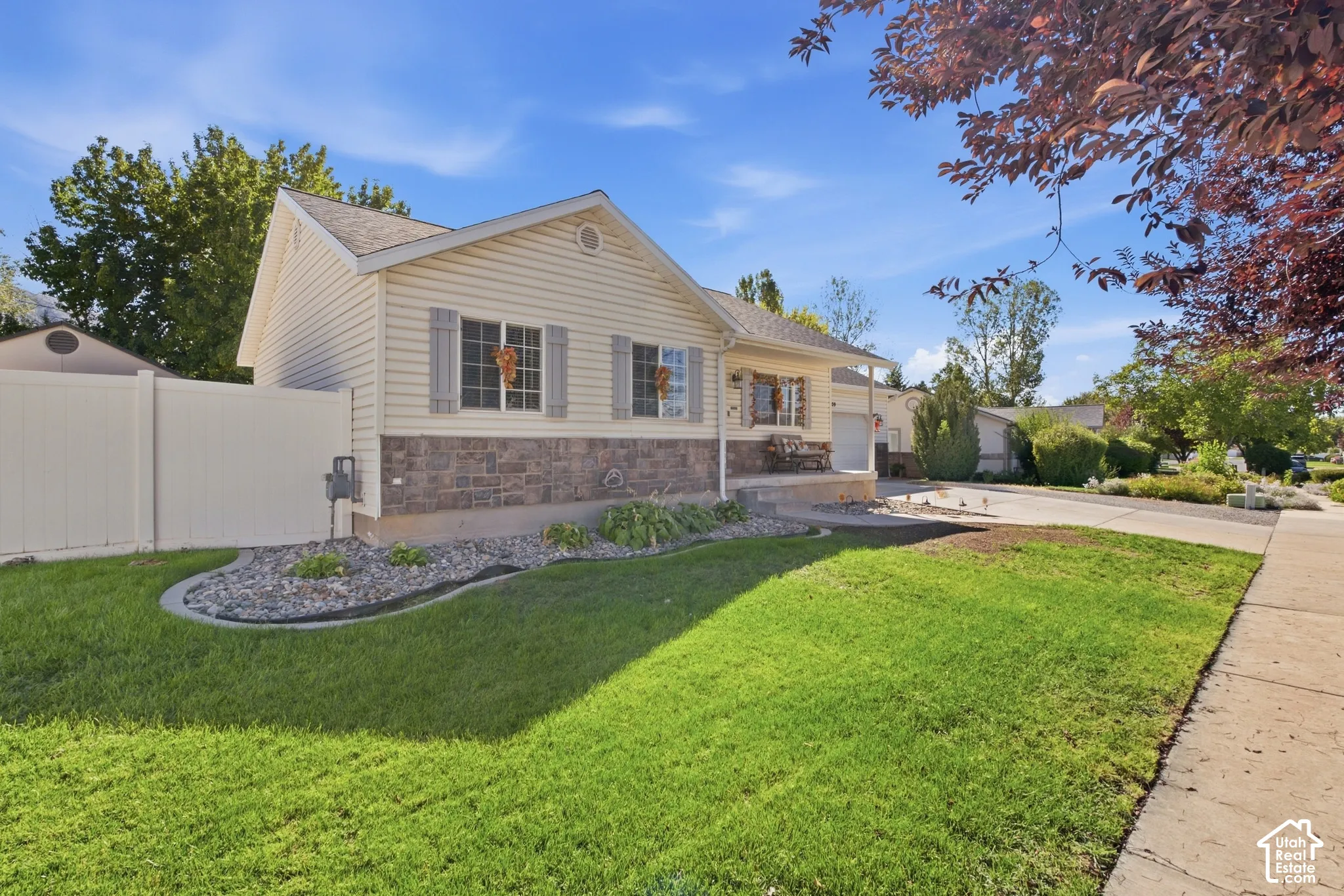 Siding exterior with decorative shutters, stone accent facade, and a fenced yard