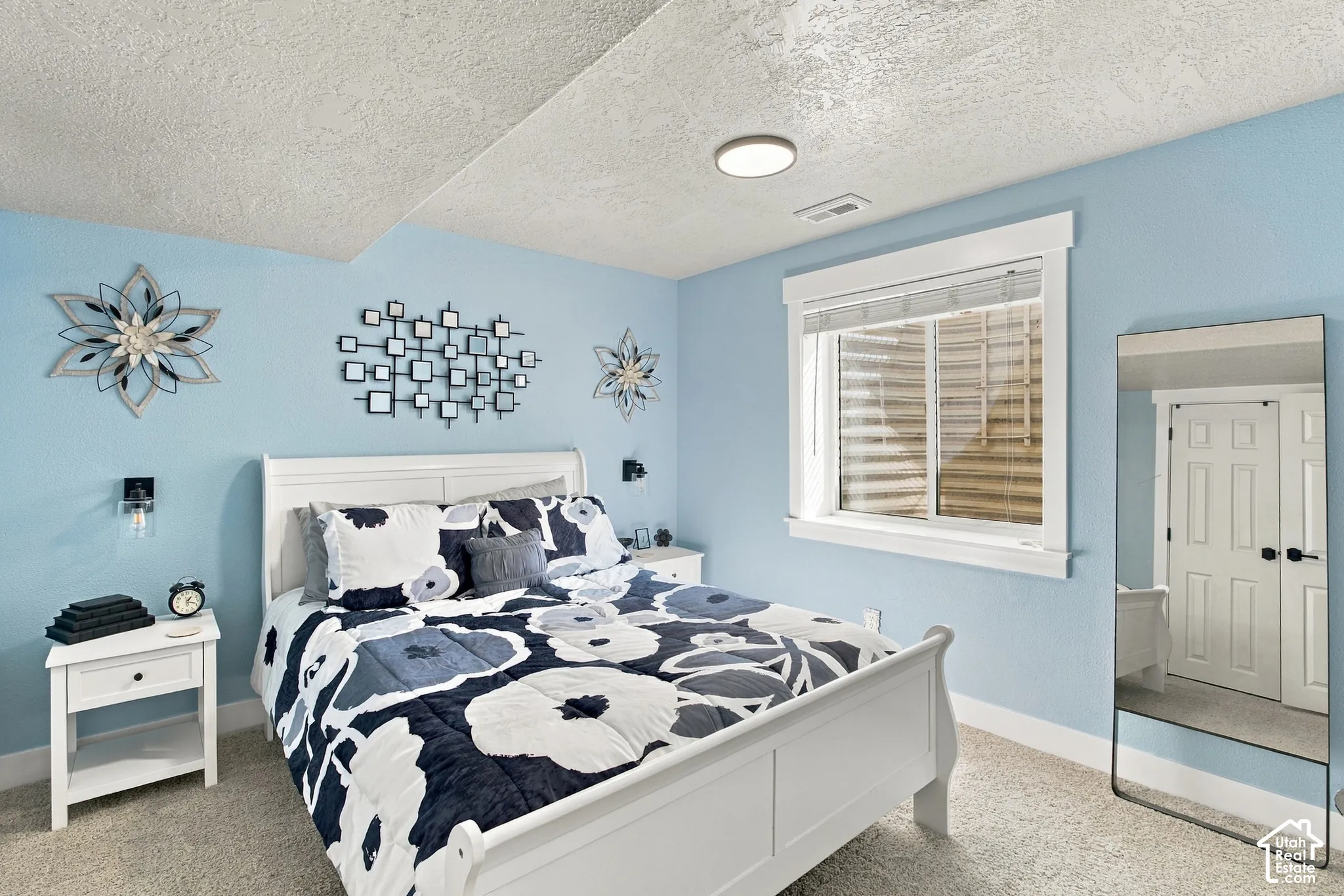 Carpeted flooring, window with white trim, built-in ceiling light, and light blue wall finish