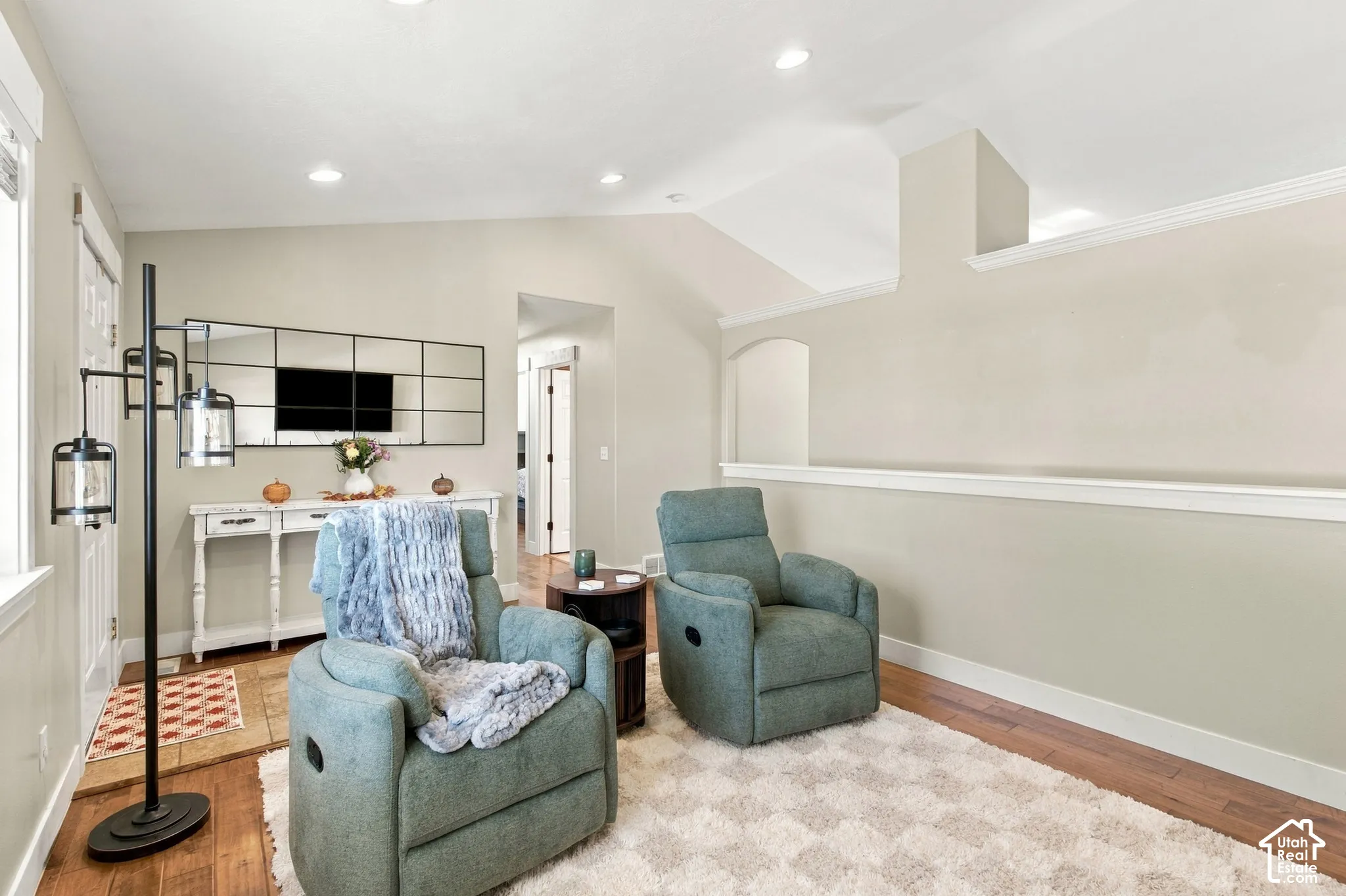 Vaulted ceiling, recessed lighting, wood-finish flooring, half wall, and accent wall