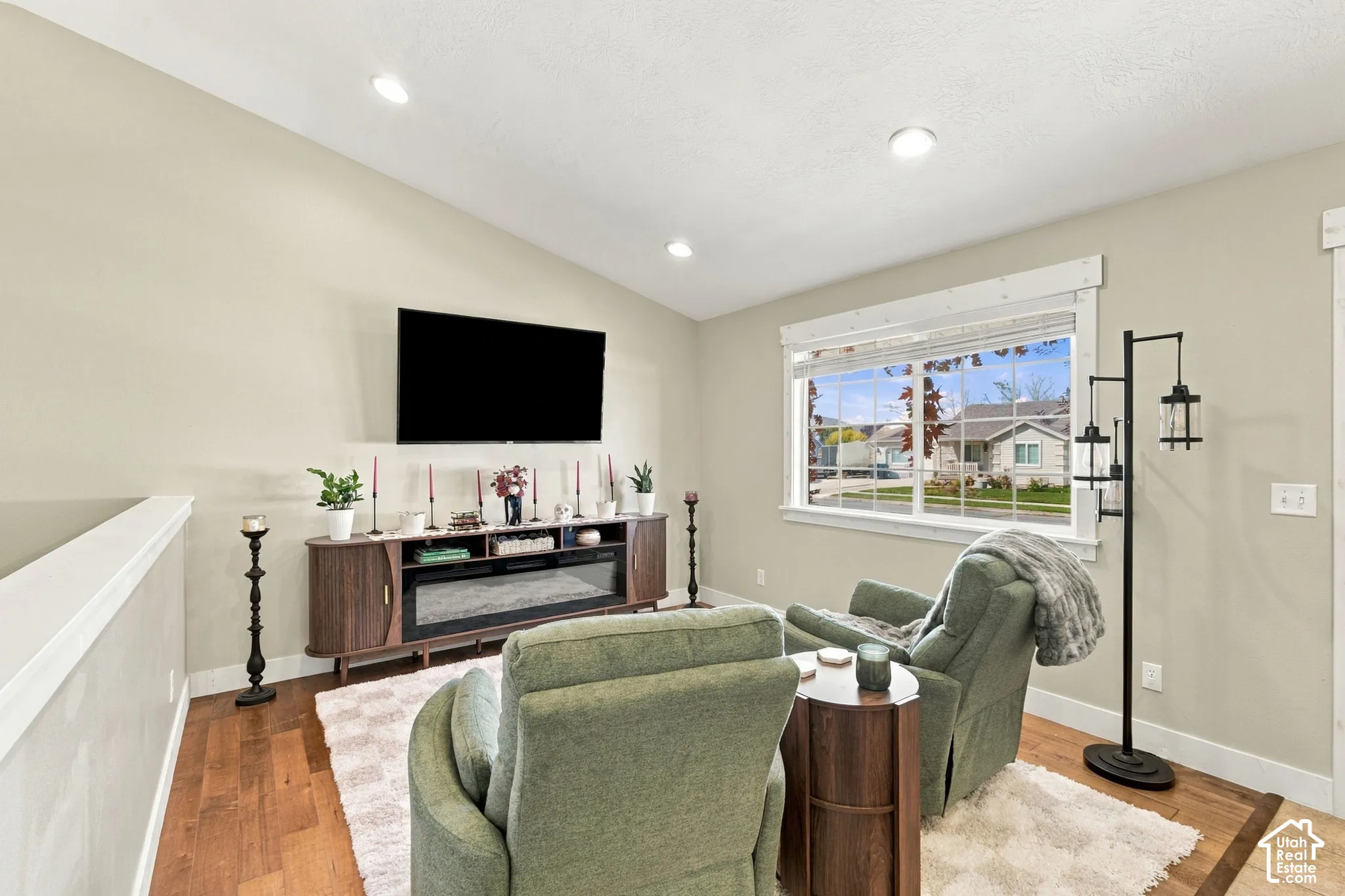Sloped ceiling, recessed lighting, wood-finish flooring, built-in electric fireplace, white-trimmed window