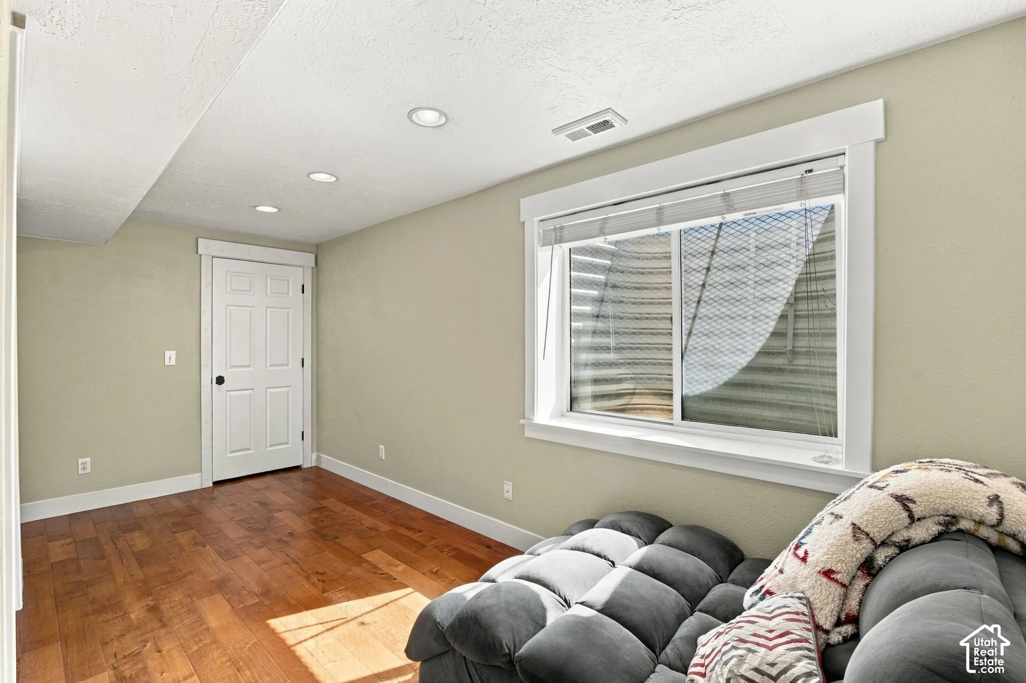 Recessed lighting, wood-finish flooring, white trim, and a white paneled door
