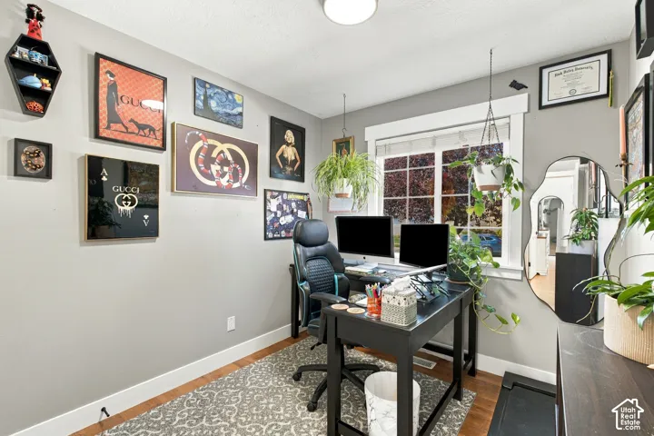 Bedroom currently used as an office with hardwood flooring neutral wall tones