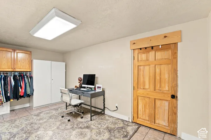 Wood panel door with black hardware, overhead wood trim, recessed lighting, and tile flooring