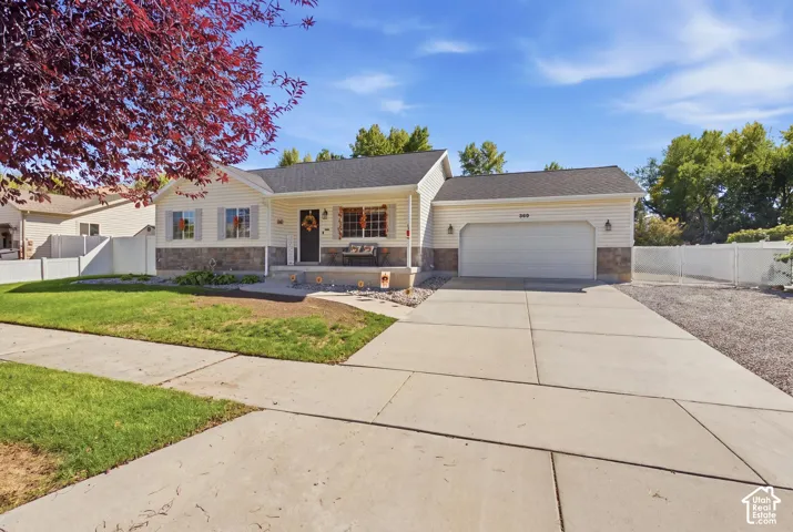 Siding exterior with stone veneer accents, a covered front porch, and an attached two-car garage